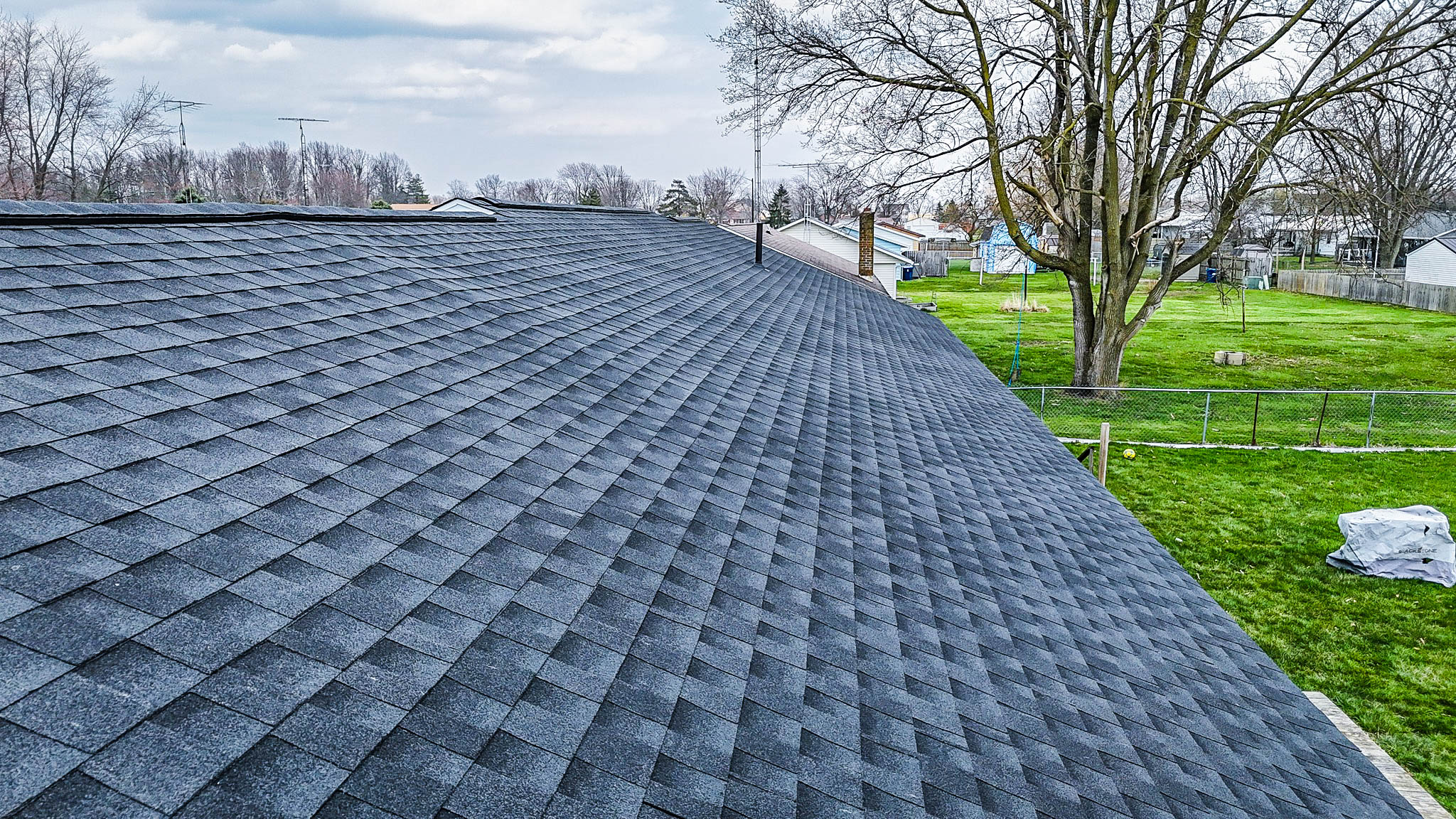 a roof installation of a house with trees and grass