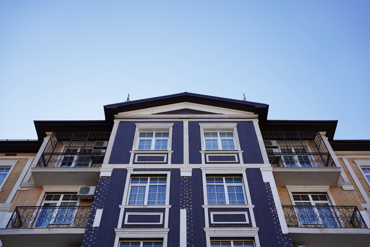 Modern three-story residential building with blue and white facade, featuring ornate balconies and classical windows