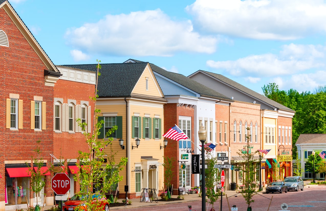 Charming small town main street with colorful brick buildings, American flags, and shops under blue sky