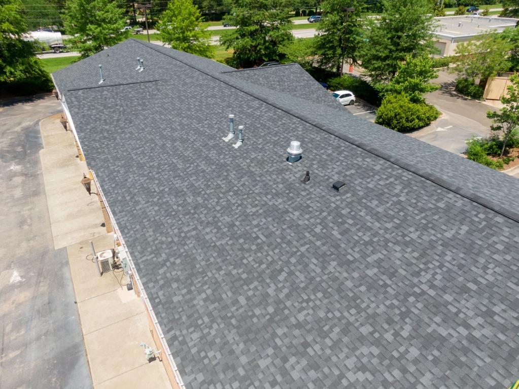 Aerial view of gray asphalt shingle roof on commercial building with vents and HVAC equipment visible
