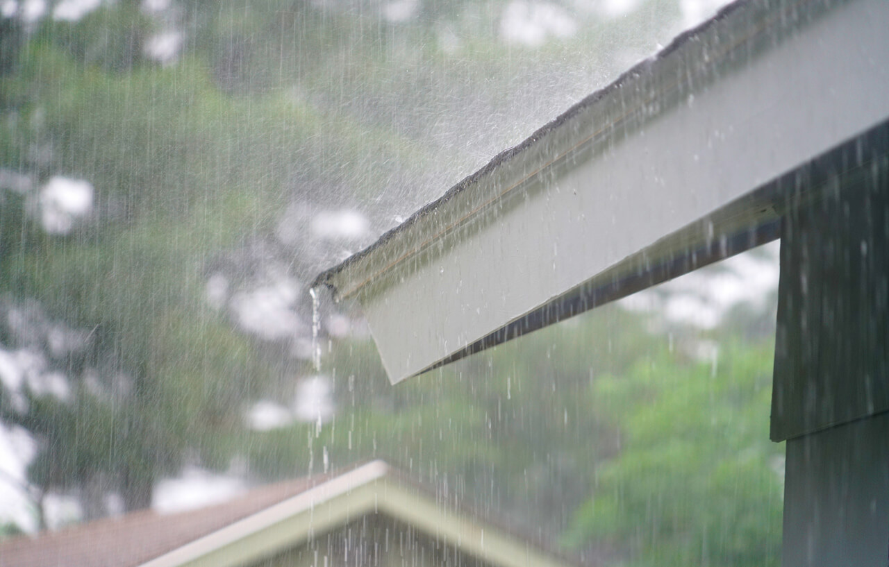 Rain pouring off a roof during a heavy downpour on a cloudy day.