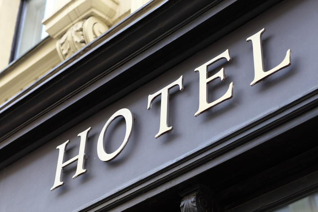 Hotel sign with white raised letters on dark exterior building facade showing classic architectural details