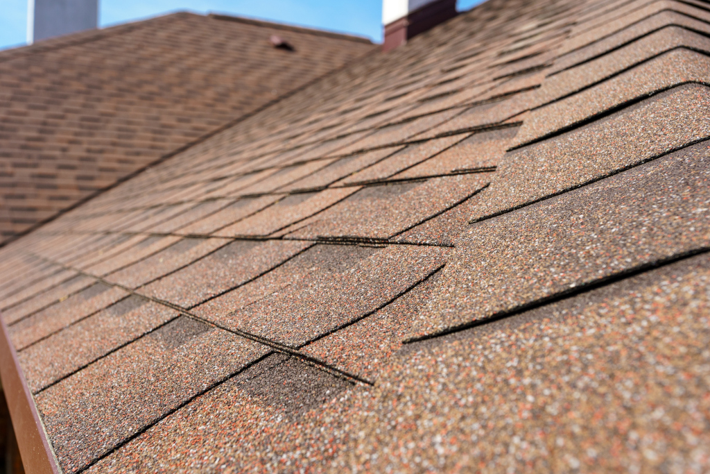 Brown asphalt roof shingles on residential house showing detailed texture and overlapping pattern installation