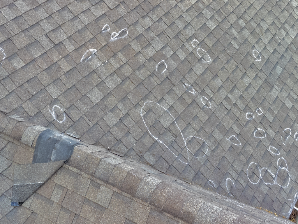 White chalk drawings and numbers scattered across gray herringbone brick pavement with concrete curb edge