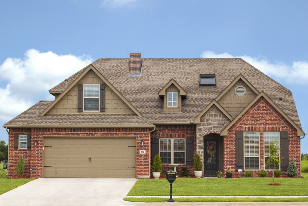 Beautiful brick and stone single-story home with brown shingle roof, attached garage, and manicured lawn