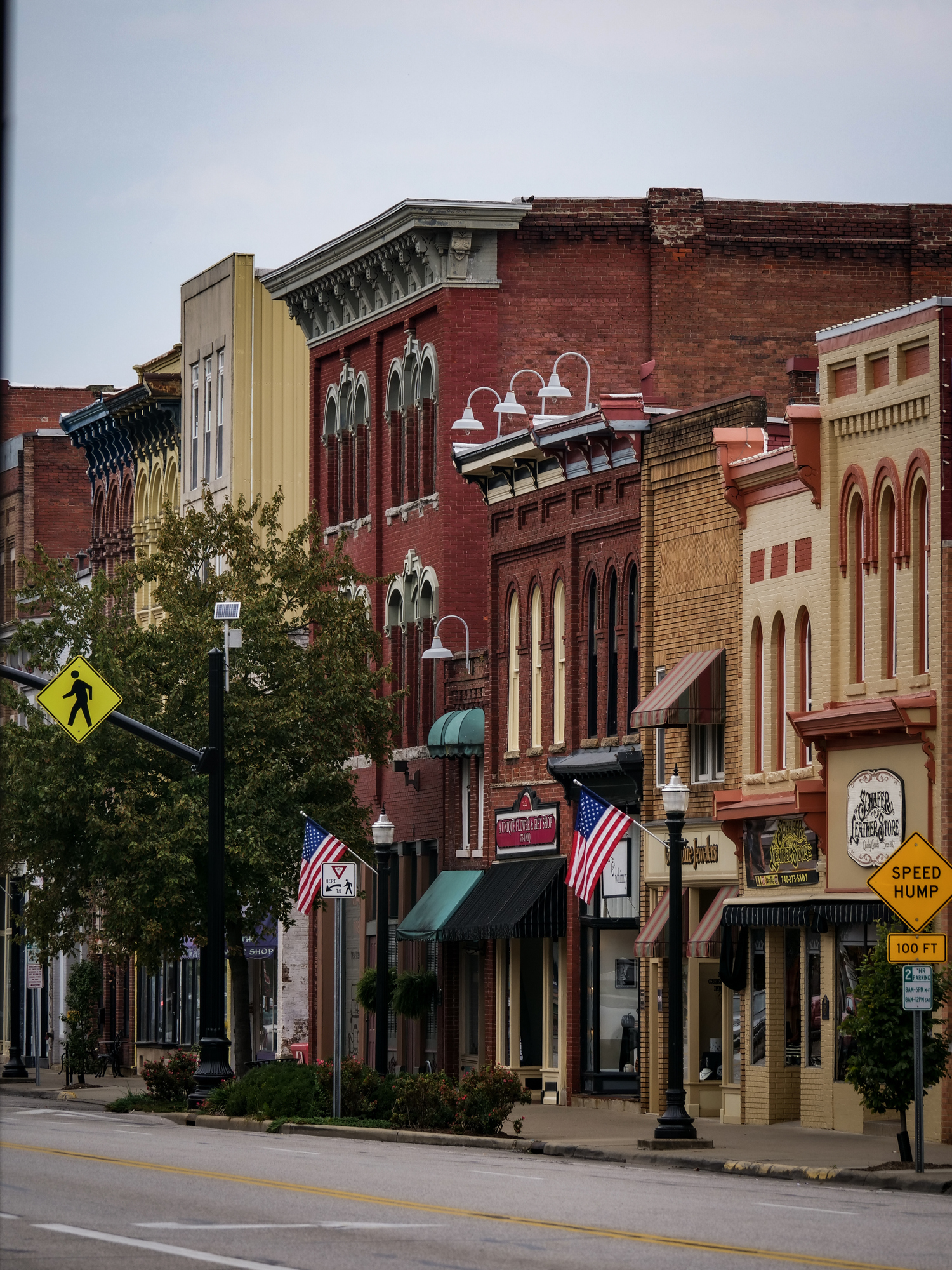 Historic downtown Main Street with Victorian brick buildings, American flags, and vintage storefronts in small town